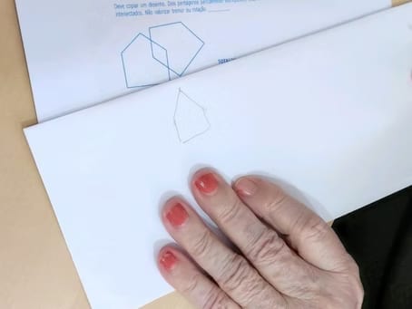 Mão de uma pessoa idosa sobre uma folha com um desenho